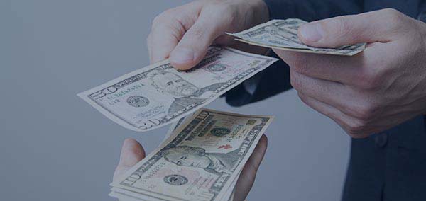 Close up of hands passing $50 dollar bill to another hand holding more money